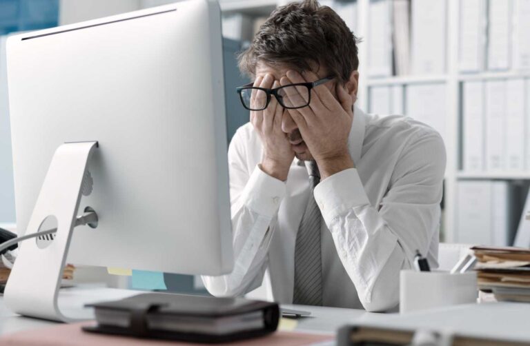 Fotografia de un hombre tapandose los ojos frente a un monitor