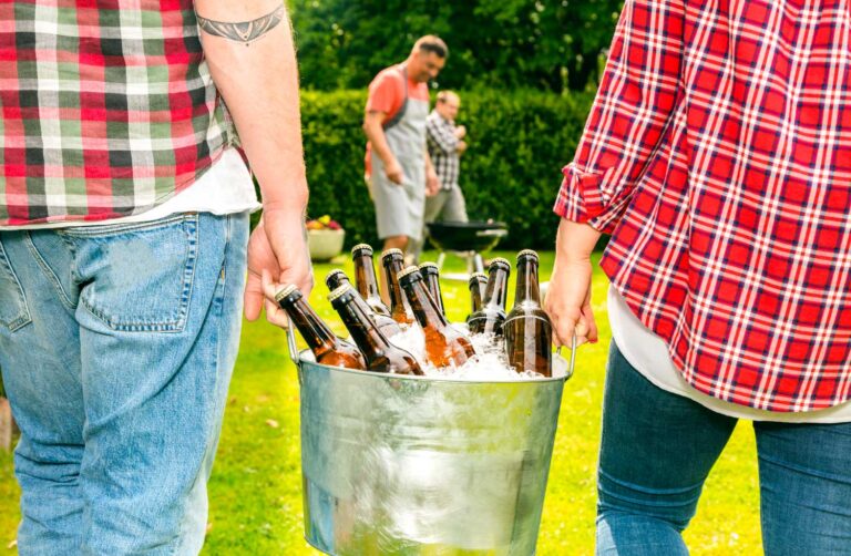 Dos personas cargando un bote con cervezas, caminado hacia un papá con su hijo