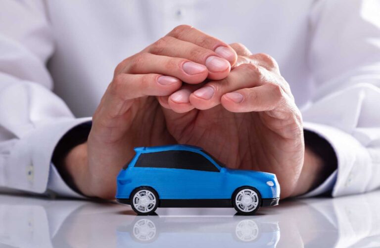 Imagen de unas manos de una persona protegiendo un automovil azul